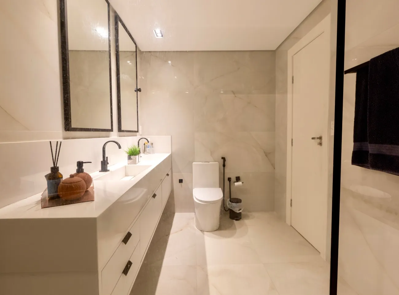 Baño claro y luminoso con mueble suspendido, inodoro suspendido y dos espejos.