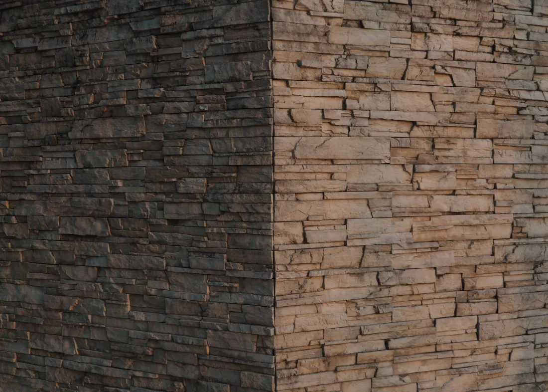 Esquina de fachada donde se encuentran dos texturas de piedra distintas.