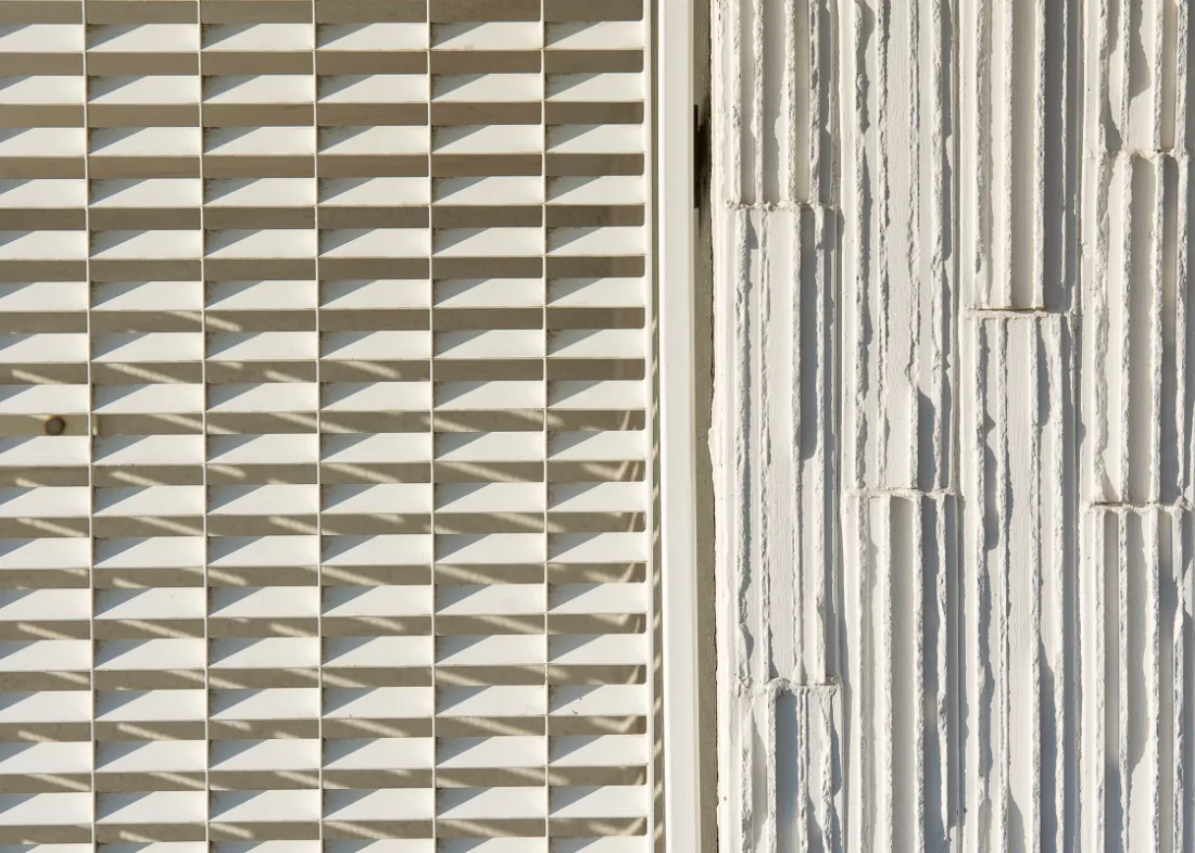 Revestimiento cerámico blanco de relieve tridimensional con la luz cayendo de lado y marcando el relieve.